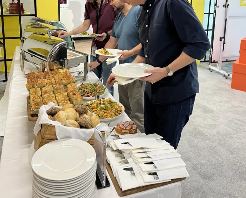 Team dishing out their meal from the buffet setup with bakery bites, salads and mains